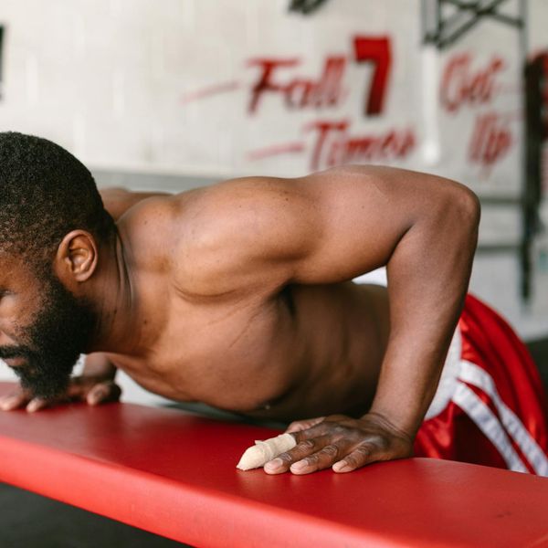 Man performing a controlled bodyweight exercise in a minimalist gym.